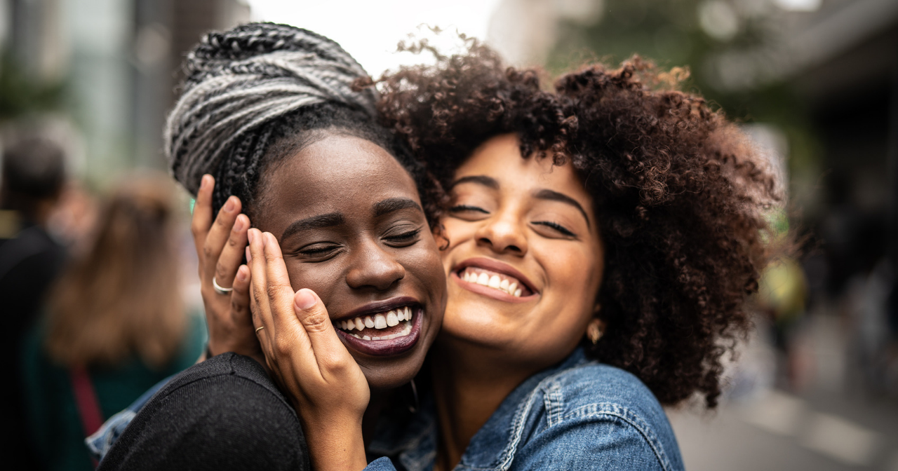 Two women hug very closely with large smiles