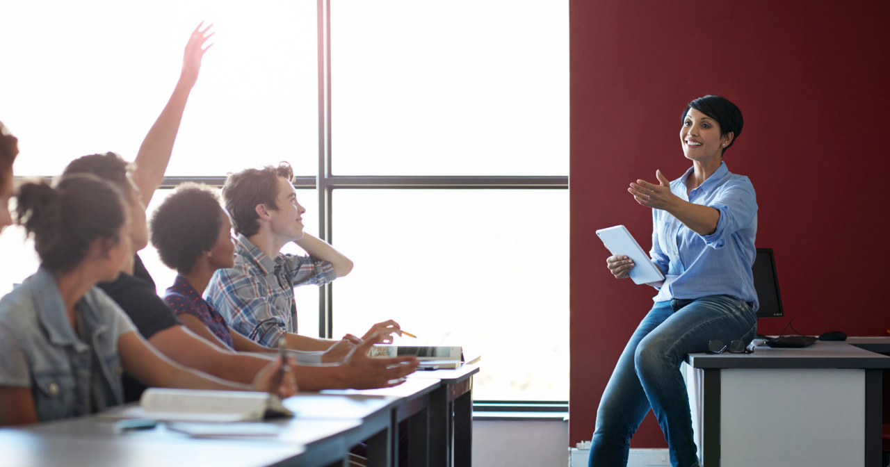 A classroom of students engaging with a smiling teacher