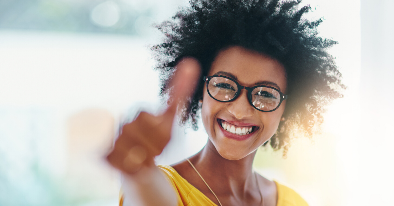 A black woman smiles and gives a thumbs up