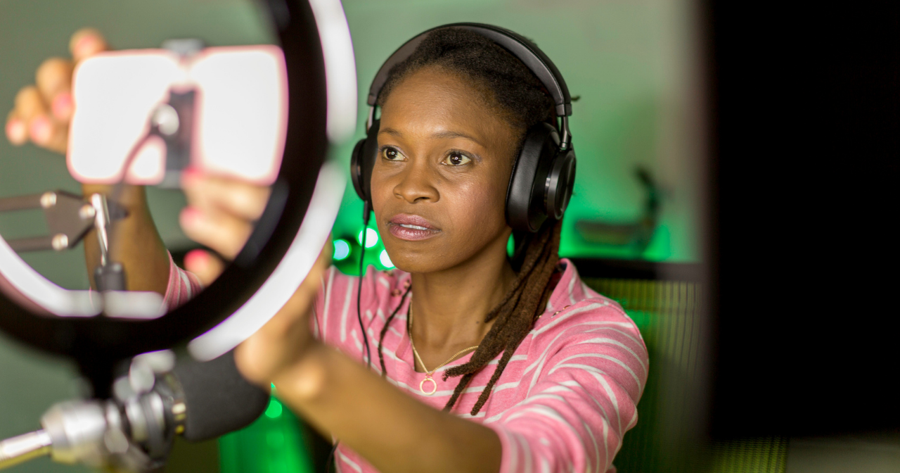 A Black women sets up a phone in a ring light. 