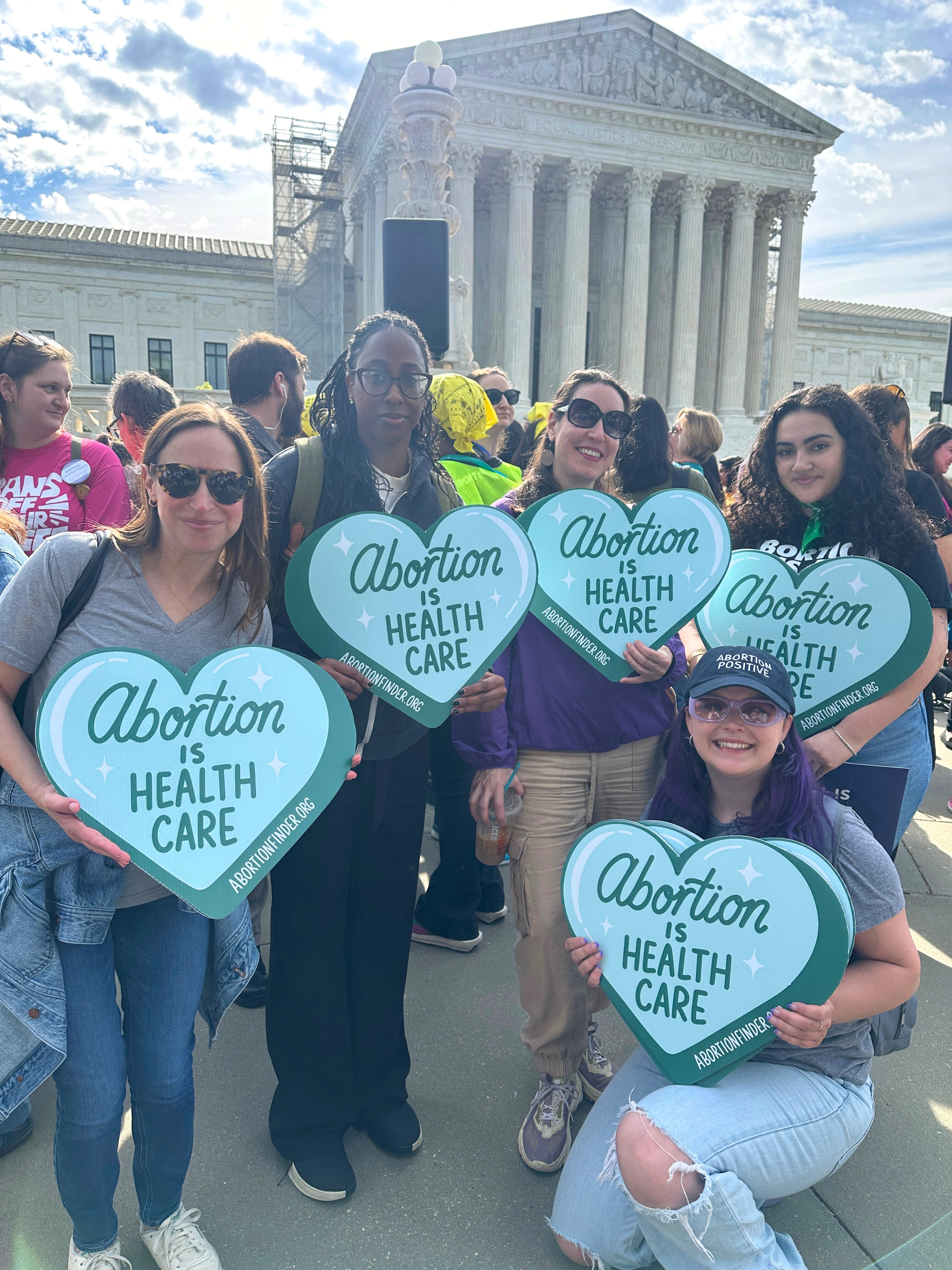 Power to Decide staff stand in front of the Supreme Court while holding abortion positive signs. 