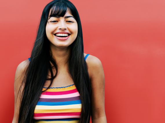 A woman smiling and laughing against a red background. 