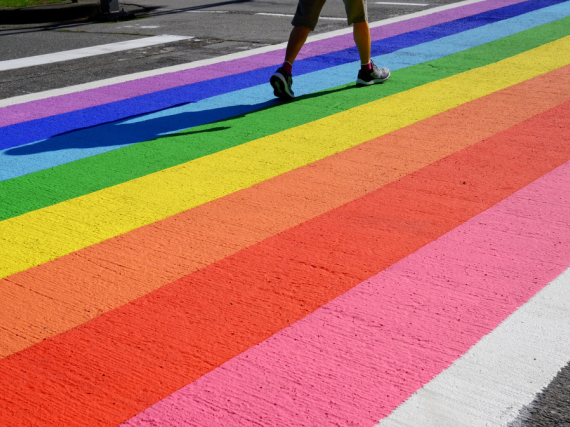 A photo of a crosswalk painted in rainbow stipes. 