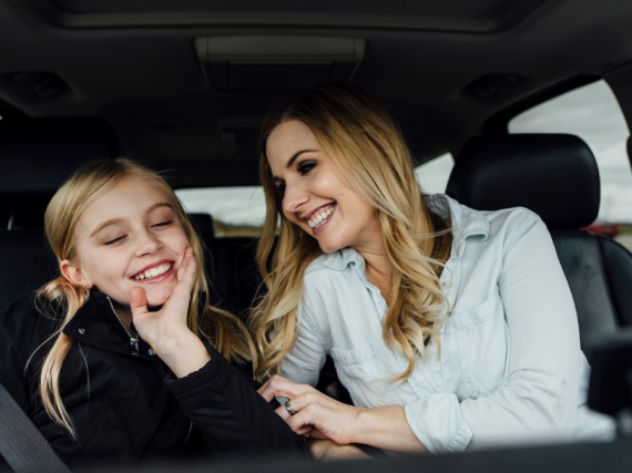 A mom and her middle school age daughter chat in the car together. 